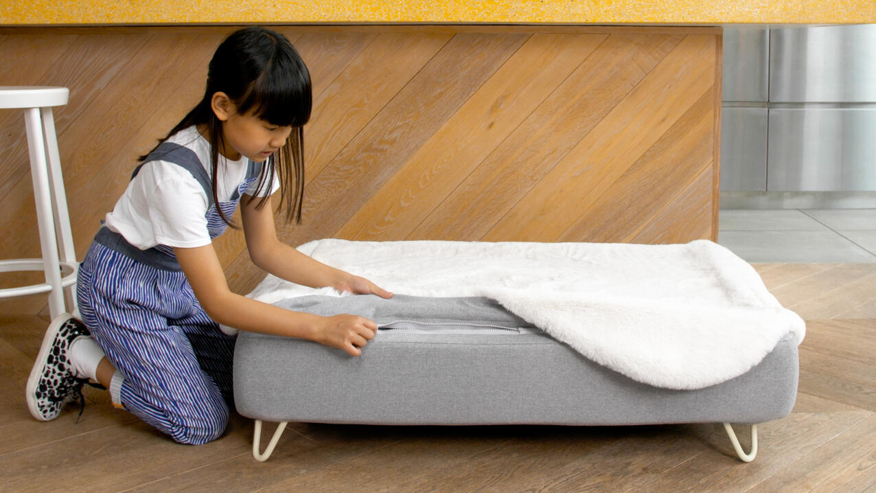 Little girl unZipping and removing Topology dog bed topper
