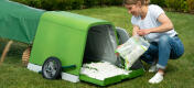 Woman refilling the bedding tray of the Eglu Go rabbit hutch