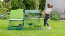 Woman moving her portable Eglu Go up chicken coop with wheels and handles