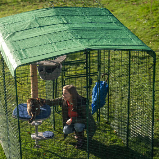 Owner and cat under a heavy duty cover in a walk in run