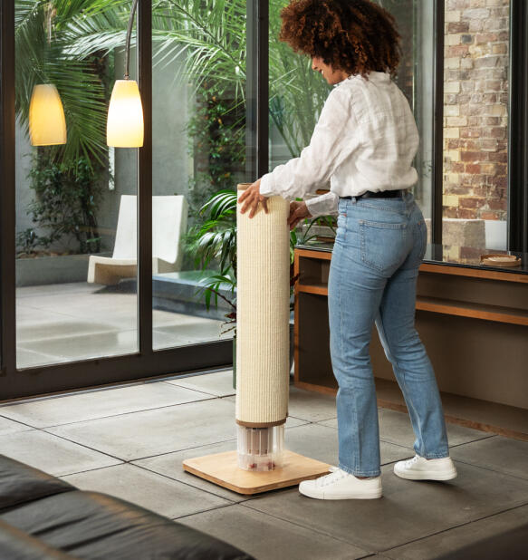 Woman assembling the Switch cat scratcher in cream with bamboo base.