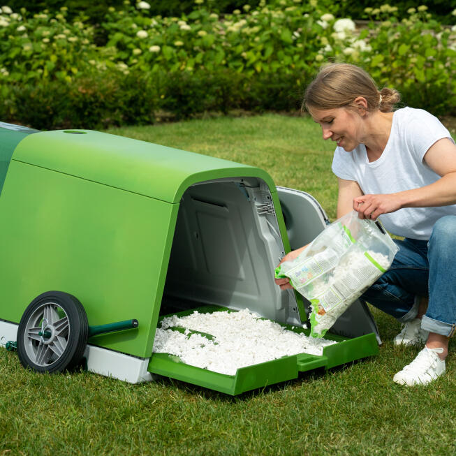 Pull out the tray to refill the bedding Woman refilling the bedding tray of the Eglu Go rabbit hutch